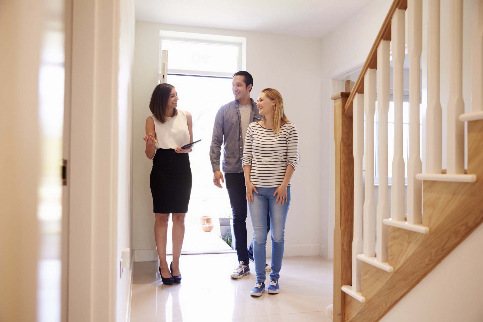 un agent immobilier fait visiter un couple. ils sont dans l'entrée d'un logement.